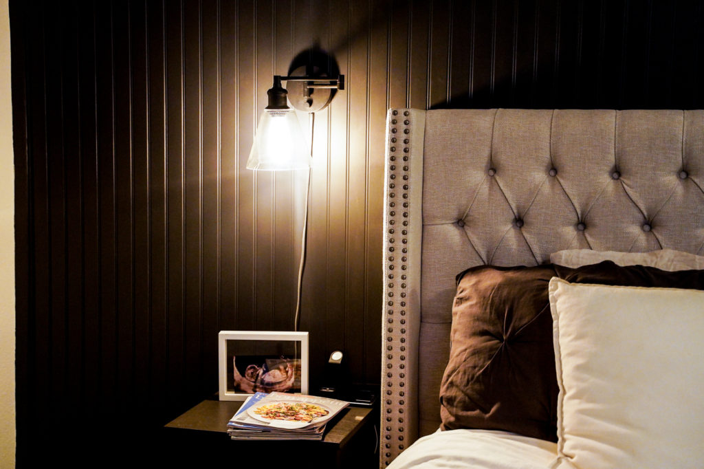 Industrial plug-in wall sconces in dark paneled bedroom